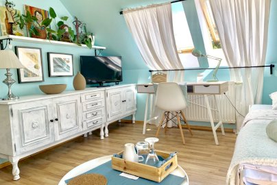 Powiększ obraz: fot. www.magnolia-rooms.pl/. Na zdjęciu łóżko, szafka, na szafce stoi telewizor, biurko z lampką i krzesełkiem