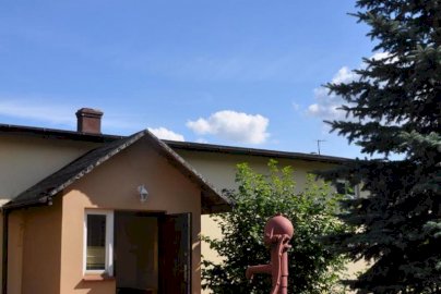 Powiększ obraz: fot. www.pokojepoddebami.pl. Pokoje Gościnne pod Dębami. Otwarte drzwi do budynku, trawnik