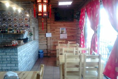 Powiększ obraz: fot. facebook Me Kong, www.facebook.com/barmekong/?ref=page_internal. Na zdjęciu wnętrze  baru Me Kong w Legionowie, stoliki z krzesełkami, ekran telewizora na ścianie, menu wiszące na ścianie