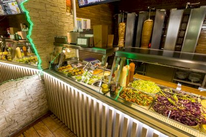 Powiększ obraz: fot. kebabking.pl/galeria/. Na zdjęciu wnętrze restauracji KEBAB KING W JABŁONNIE, za ladą dania mięsne, sałatki