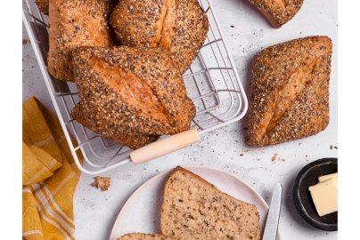 Powiększ obraz: fot. Piekarnie Cukiernie Putka, www.facebook.com/media/set/?set=a.261761570600972&type=3. Na zdjęciu pieczywo bułki, bułka przekrojona na pół, obok bułki nóż, masło na bułce, na czarnym talerzyku masło