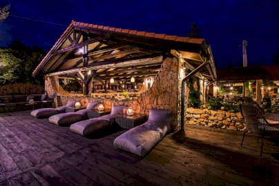 Powiększ obraz: fot. www.zlotylin.pl/. Na zdjęciu restauracja Złoty Lin w Wierzbicy, obok oświetlonej wiaty łóżka z poduszkami do odpoczynku na tarasie, wiklinowe fotele do siedzenia, z tyłu w tle maszt