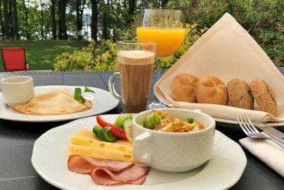 Powiększ obraz: fot. www.hotelpantadeusz.pl/restauracja. Na zdjęciu bułki, śniadanie, plastry szynki i sera żółtego, sztućce, leżaki  z przodu
