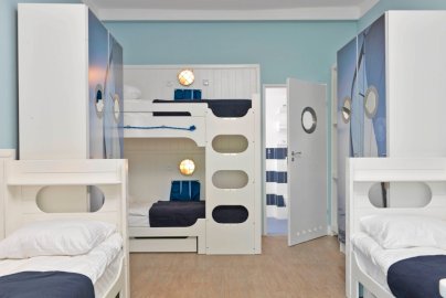 Powiększ obraz: fot. www.klubmila.pl. Na zdjęciu pokój sypialny z łóżkami pojedynczymi oraz piętrowymi, po obu stronach pokoju szafki
