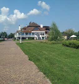 Powiększ obraz: fot. www.restauracjaparasol.pl. Restauracja Parasol widziana z oddali, chodnik z kostki brukowej prowadzący do hotelu, trawnik