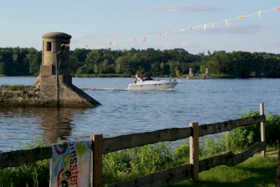 Powiększ obraz: fot. facebook Przystań Przy Starym Moście. Na zdjęciu element starego mostu na Narwi w Zegrzu, łódź  motorowa pływa po Zalewie Zegrzyńskim