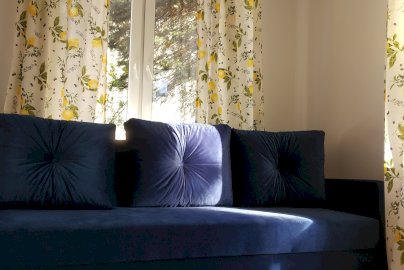 Powiększ obraz: fot. Forest House. Na zdjęciu granatowa kanapa, wyżej okno