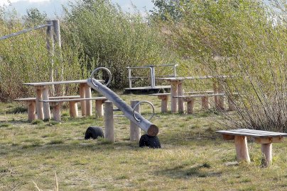 Powiększ obraz: fot. Krzysztof Kozań. Na zdjęciu huśtawka oparta na podłożu na oponach, drabinki, drewniane ławki z miejscami do siedzenia, karuzela