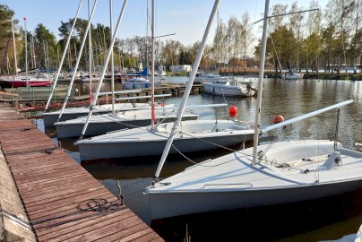 Powiększ obraz: fot. https://ykpwarszawa.pl/port-pilawa/. Na zdjęciu łodzie do żeglowania przycumowane do brzegu do pomostu