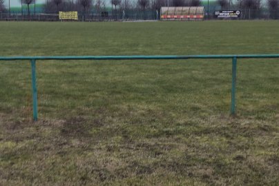 Powiększ obraz: fot. Krzysztof Kozań. Boisko o nawierzchni trawiastej do piłki nożnej, z tyłu ławki dla trenerów, sztabu szkoleniowego piłkarskiego