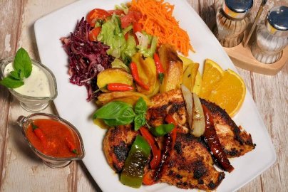 Powiększ obraz: fot. facebook Urfa Kebab Legionowo, https://www.facebook.com/urfa.kebab2021/. Na zdjęciu danie z mięsa, z ziemniakami, surówką z tartej marchewki, czerwonej kapusty , sosy, obok solniczka, pieprzniczka