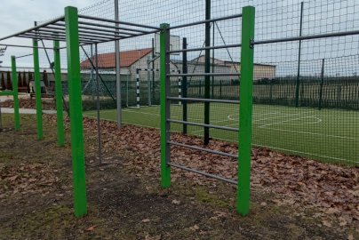 Powiększ obraz: fot. Krzysztof Kozań. Na zdjęciu elementy street workout, wyposażenia siłowni zewnętrznej  w Dębem, drążki do podciągania, drabinki równoległe poziome, z tyłu boisko do gry w piłkę nożną, koszykową, po lewej stronie z tyłu stolik do gry w szachy, warcaby, plac zabaw dla dzieci