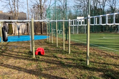 Powiększ obraz: fot. Krzysztof Kozań. Na zdjęciu drążki, poręcze do podciągania się nachwytem, podchwytem, podciągania równoległego, kółka gimnastyczne, worek bokserski, obok boisko do piłki nożnej oraz koszykowej, za placem do ćwiczeń budynek mieszkalny