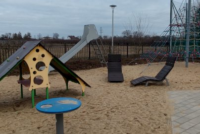 Powiększ obraz: fot. Krzysztof Kozań. Na zdjęciu  urządzenia zabawowe na placu zabaw w Dębem, zjeżdżalnia, leżaki drewniane, ścianka wspinaczkowa