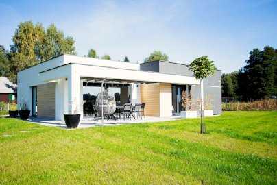 Powiększ obraz: fot. facebook Dom na Cuplu, https://www.facebook.com/photo/?fbid=276069411183916&set=pcb.276070777850446. Na zdjęciu dom, taras, ogród, stolik z krzesłami na tarasie