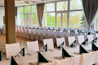 Powiększ obraz: fot. geovita.pl/nasze-obiekty/jadwisin/. Na zdjęciu zastawa stołowa: kieliszki, sztućce, zielone chusty na stołach, widok na salę restauracyjną